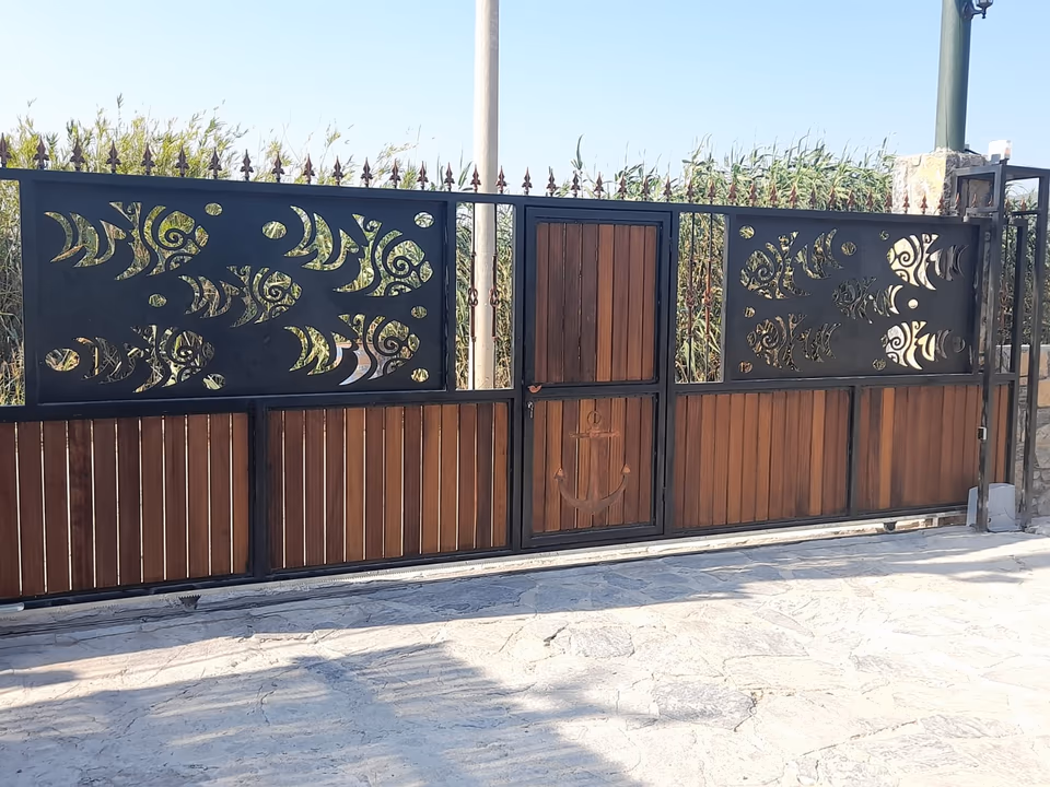 Ahşap panelli, altın tonunda desenli siyah bahçe kapısı