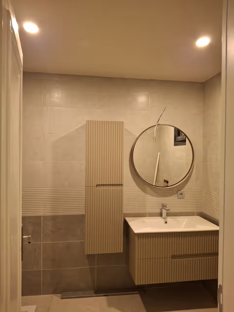Banyo dolabı, yuvarlak ayna ve seramik duvar