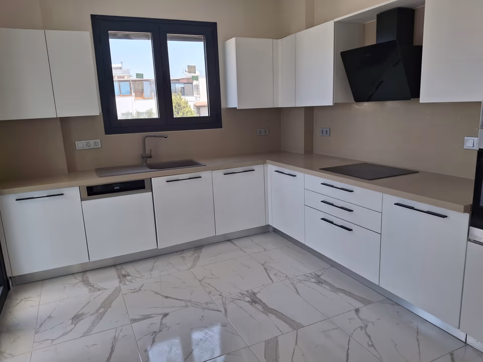 Beyaz mutfak dolapları ve koyu renkli davlumbaz