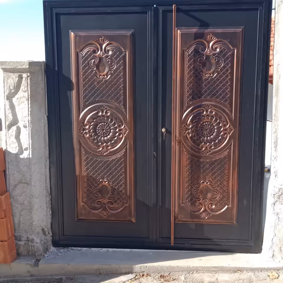 Bakır tonunda kabartmalı panellere sahip çift kanatlı metal kapı