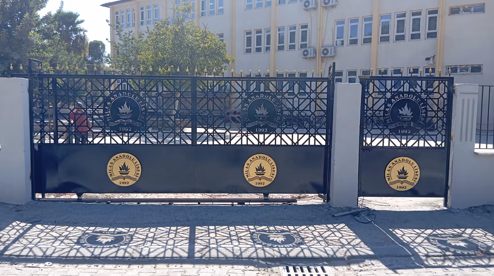 Dairesel amblem ve geometrik desenlere sahip çift kanatlı metal kapı