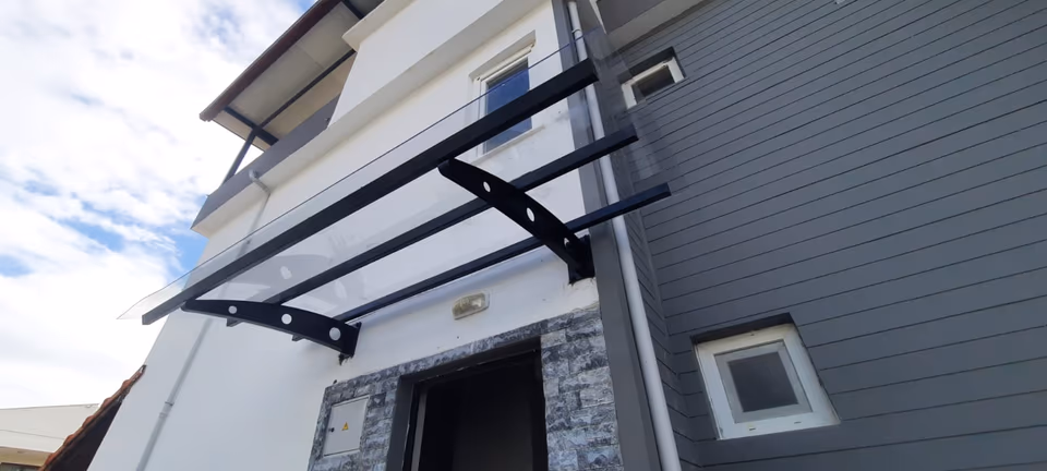 Konut girişinde metal taşıyıcılı cam sundurma